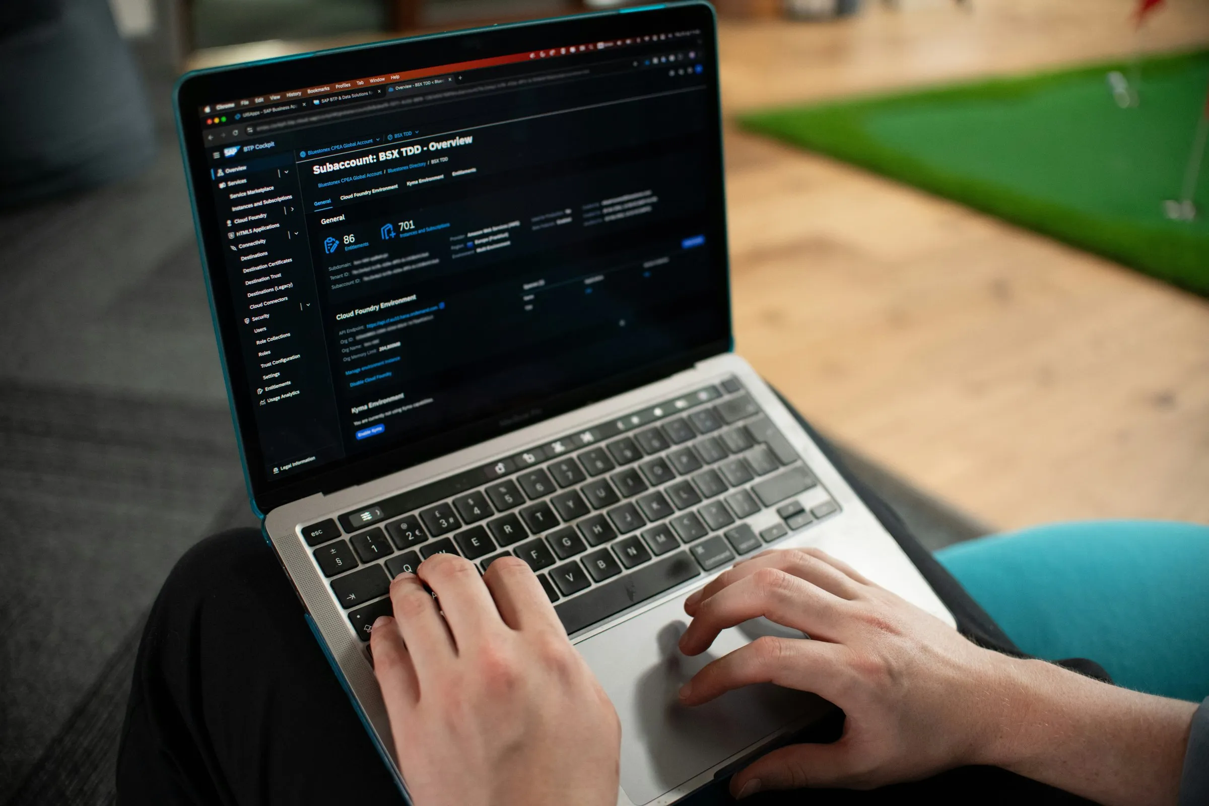 Hands typing on a laptop keyboard, a dashboard with customer data visible on the screen