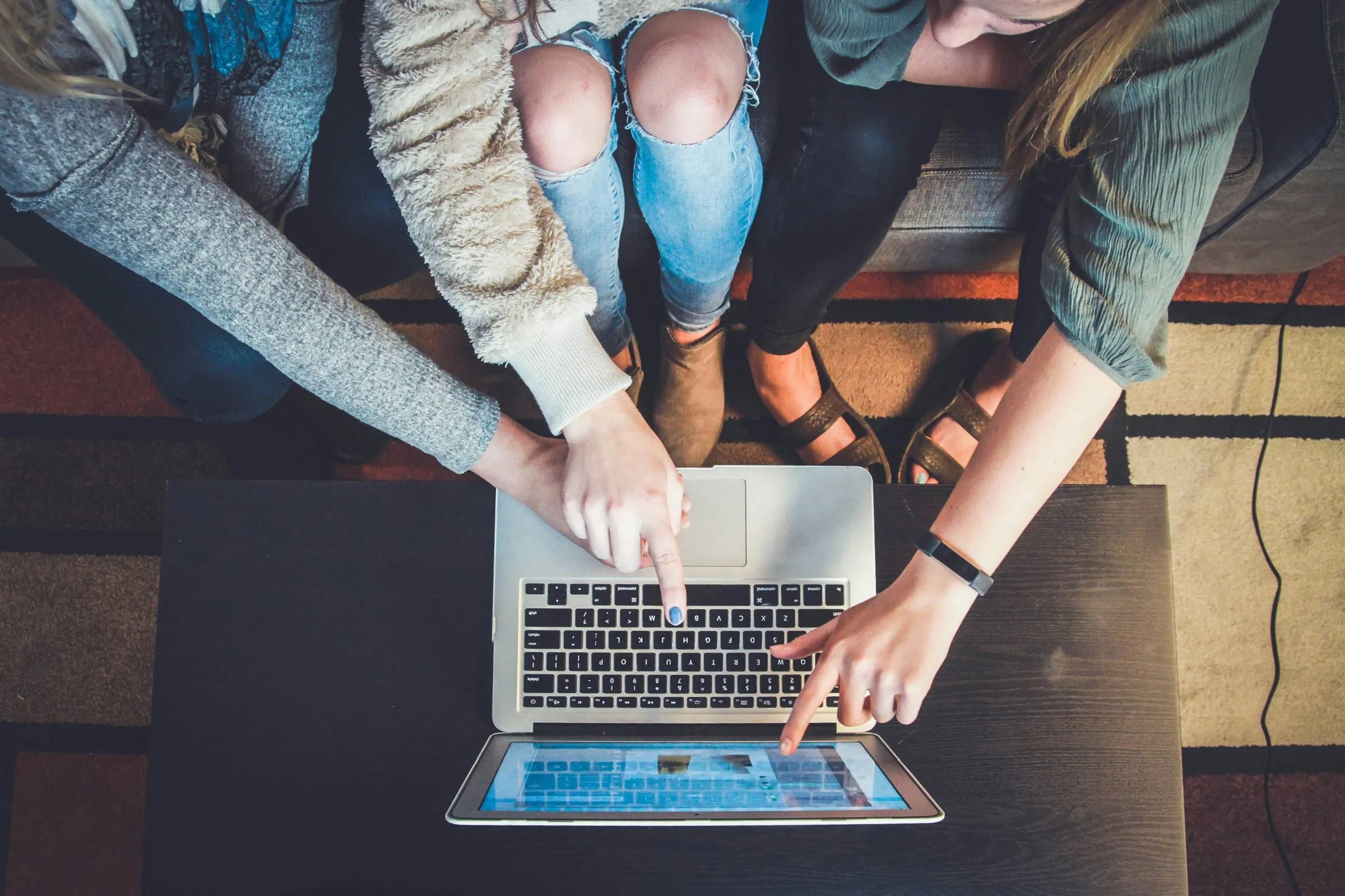 Several hands working together at a laptop