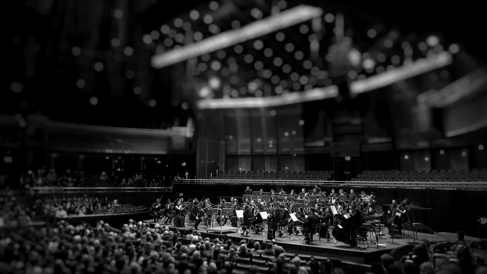Black-and-white photo of an orchestra on stage in a large concert hall